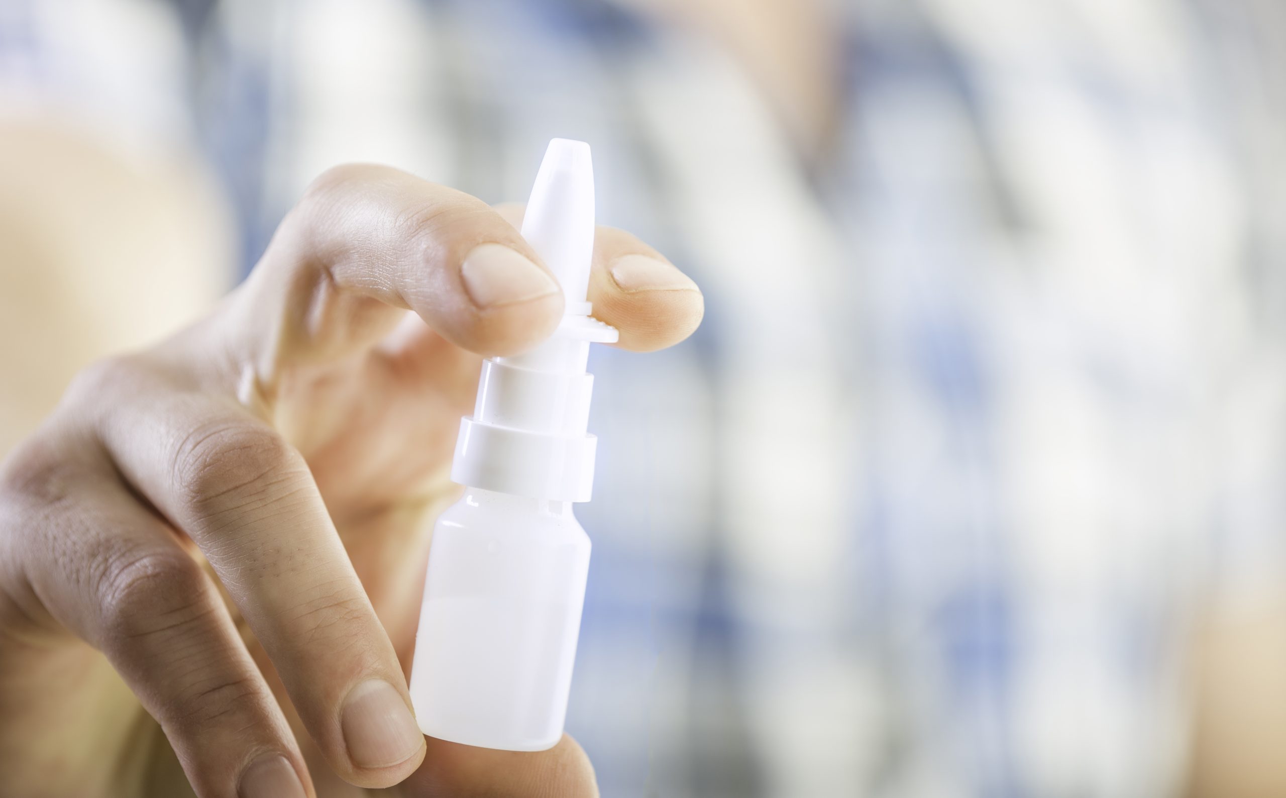 A person holding a nasal spray bottle. Alzheimer's nasal spray.